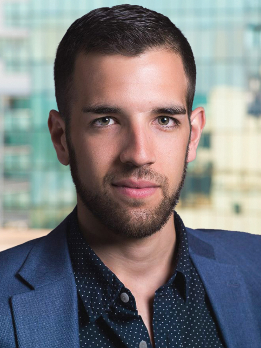 Male realtor headshot inside Manhattan office with skyscraper window view, NYC real estate agent