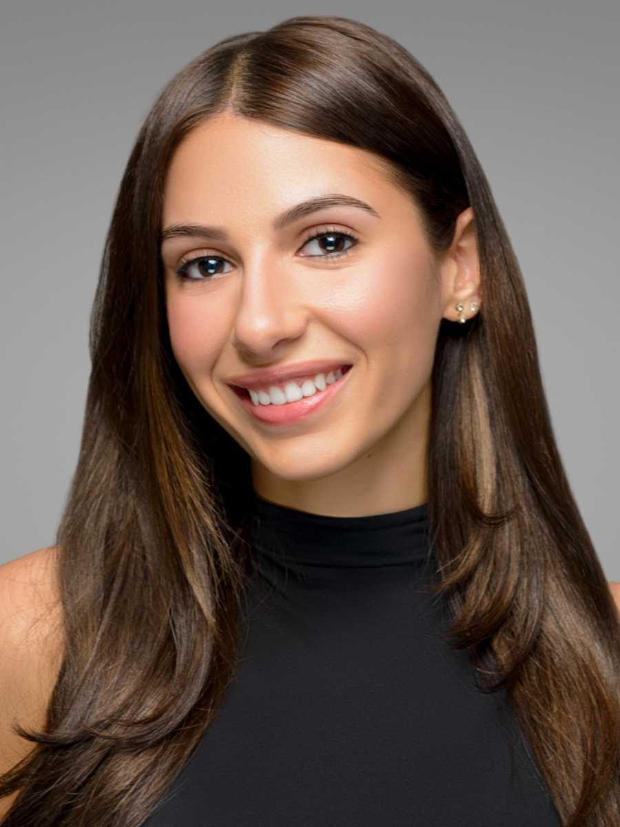 Female real estate agent headshot in Astoria NYC studio with light gray backdrop, professional smile