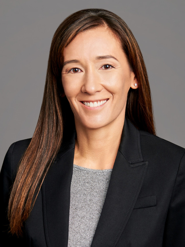 Business headshot of a female finance executive on a gray background in NYC